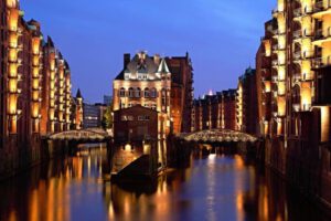 Beleuchtete Wasserschloss mit der Speicherstadt als Kulisse.