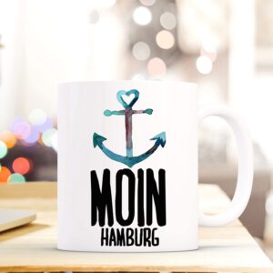 Eine Kaffee Tasse mit der Aufschrift: Moin Hamburg. In einem Farbpinselaufstrich gehalten